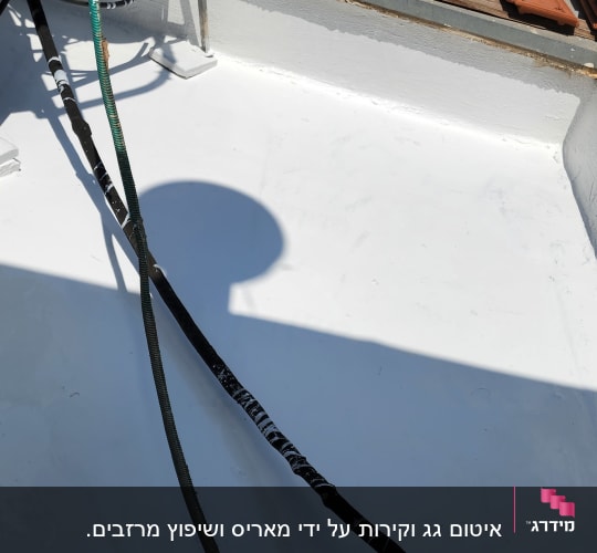 צינורות על גג אטום בלבן עם צללים